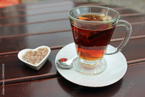 Glass cup of black tea including tea bag and sugar