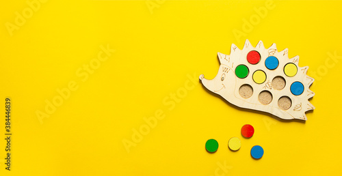 on a yellow bright background lies a children's wooden educational toy. hedgehog and colored circles. studying flowers