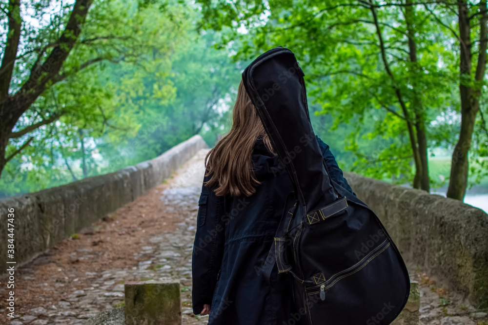 Young girl carry guitar bag while walking alone in naure Young girl carry guitar bag while walking alone in naure