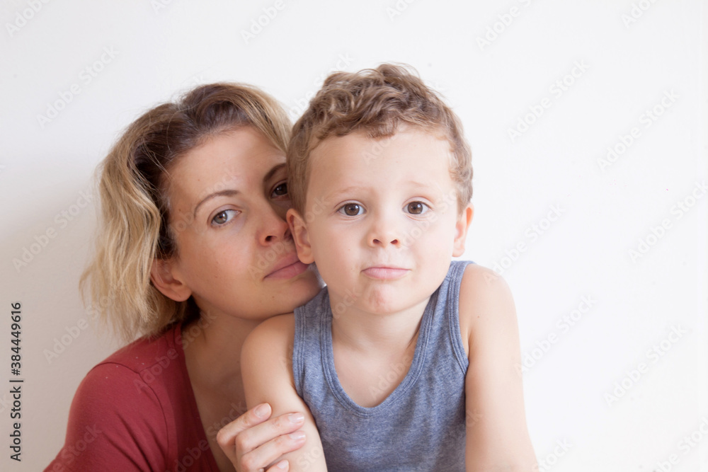 Portrait of happy mother with cute kids boy sitting on a light background. Happy family concept. Portrait of happy mother with cute kids boy sitting on a light background. Happy family concept.