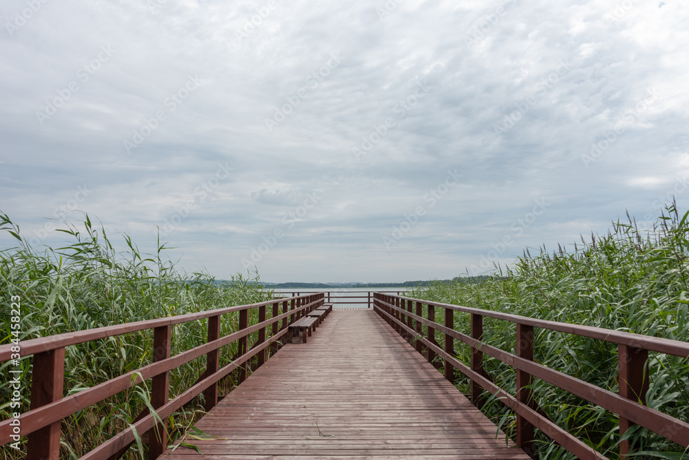 Wooden pier under cloudy sky on Lake Jamno, Mielno, Poland. 