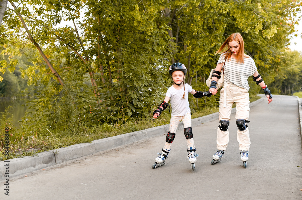 Young mother and her daughter rollerskating in summer day Young mother and her daughter rollerskating in summer day