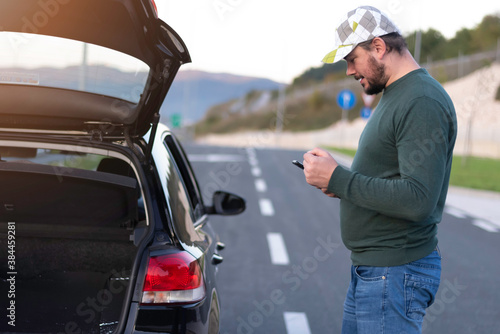 Man calling road assistance on the highway. Calling car service, assistance or tow truck while having troubles with his car.
