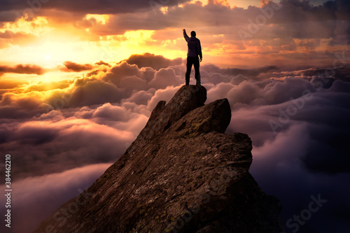 Fantasy Adventure Composite with a Man on top of a Mountain Cliff with Dramatic Cloudscape in Background during Sunset or Sunrise. Concept  Hike  Freedom  Explore  Journey