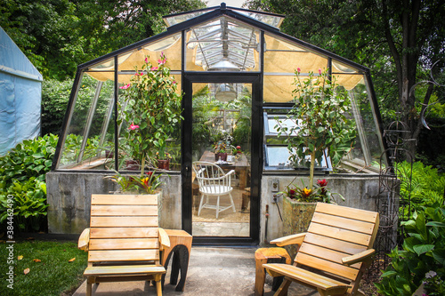 Cute and homey greenhouse used as an outdoor room surrounded by trees and foliage