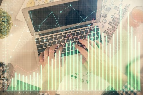 Double exposure of man's hands typing over laptop keyboard and forex chart hologram drawing. Top view. Financial markets concept.