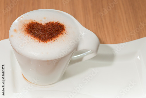 Cup of coffee with cinnamon heart on milk foam