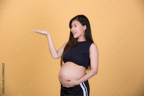 Portrait of Beautiful pregnant woman asia young woman,isolated on yellew background. Human face expressions, emotions feelings, body language,beauty and fashion concept. photo
