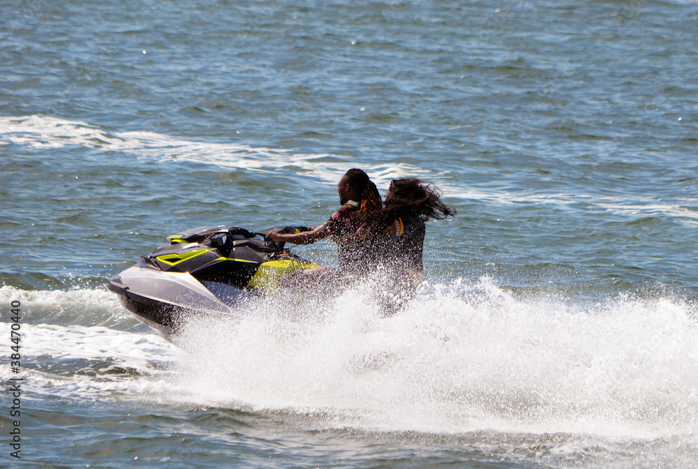 Afro-American couple riding tandem on a speeding jet ski. Afro-American couple riding tandem on a speeding jet ski.