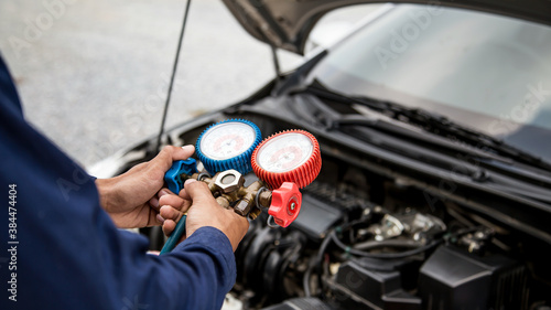 Auto mechanic are using measuring equipment tool for filling car air conditioners. Concepts of car care fix checking repair service and insurance.