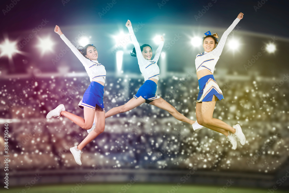 Group of beautiful cheerleaders jumping in stadium