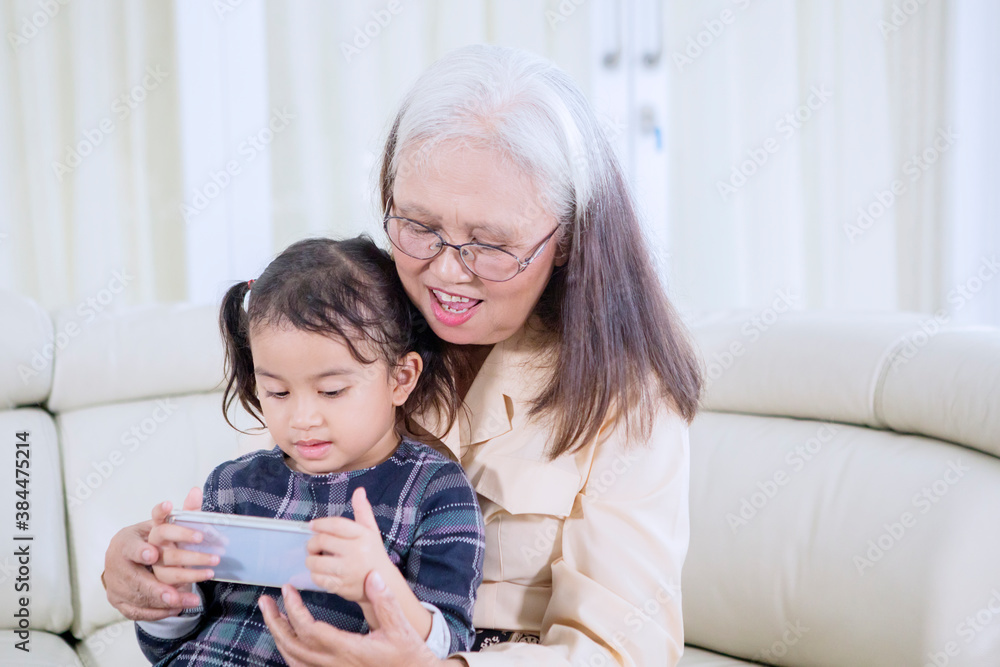 Old woman with her grandchild using a mobile phone Old woman with her grandchild using a mobile phone