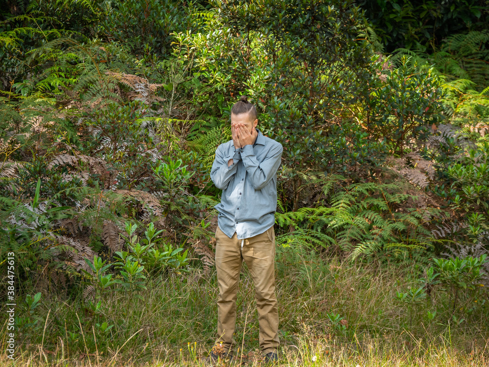 Caucasian Blond Man is Standing Covering his Eyes in the Middle of the Nature Caucasian Blond Man is Standing Covering his Eyes in the Middle of the Nature