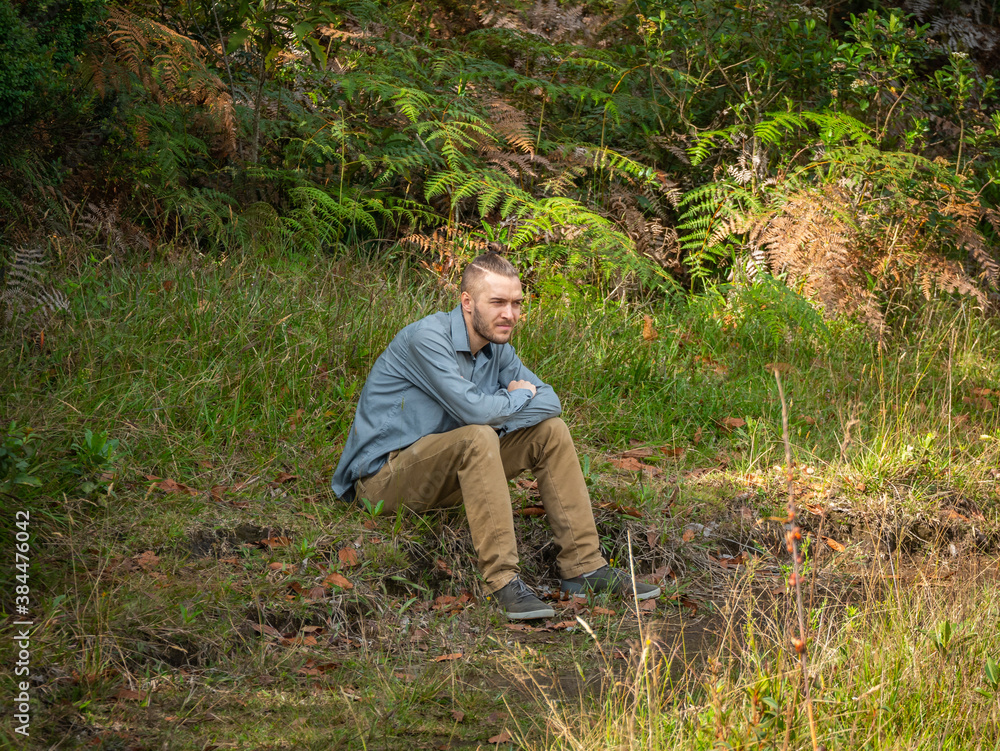 Caucasian Blond Man is Sitting in the Ground in the Middle of the Nature