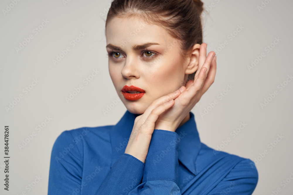 Portrait of a beautiful woman with red lips on a light background and a blue shirt cropped view Portrait of a beautiful woman with red lips on a light background and a blue shirt cropped view