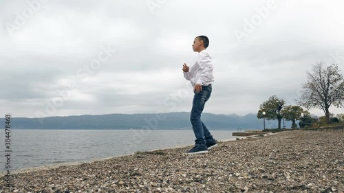 The boy collects stones and throws into the water. Slow motion