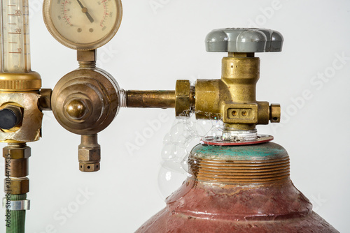 Gas cylinder for industrial welding with dial, valve and nozzle with bubble of leak