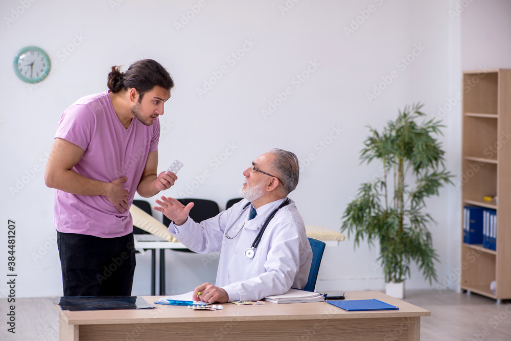 Fototapeta premium Young male patient visiting old male doctor
