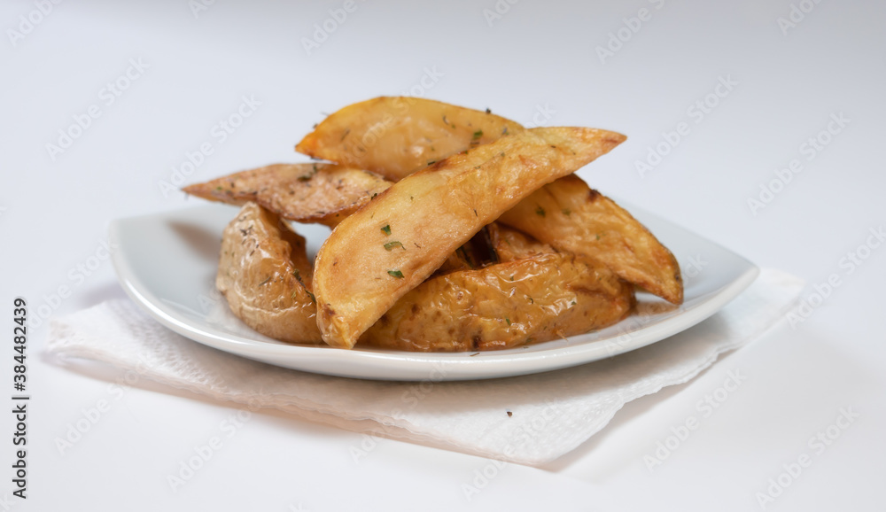 Rustic or Country Style Herb Fries potatoes on a Small Plate on a White Surface or background Rustic or Country Style Herb Fries potatoes on a Small Plate on a White Surface or background