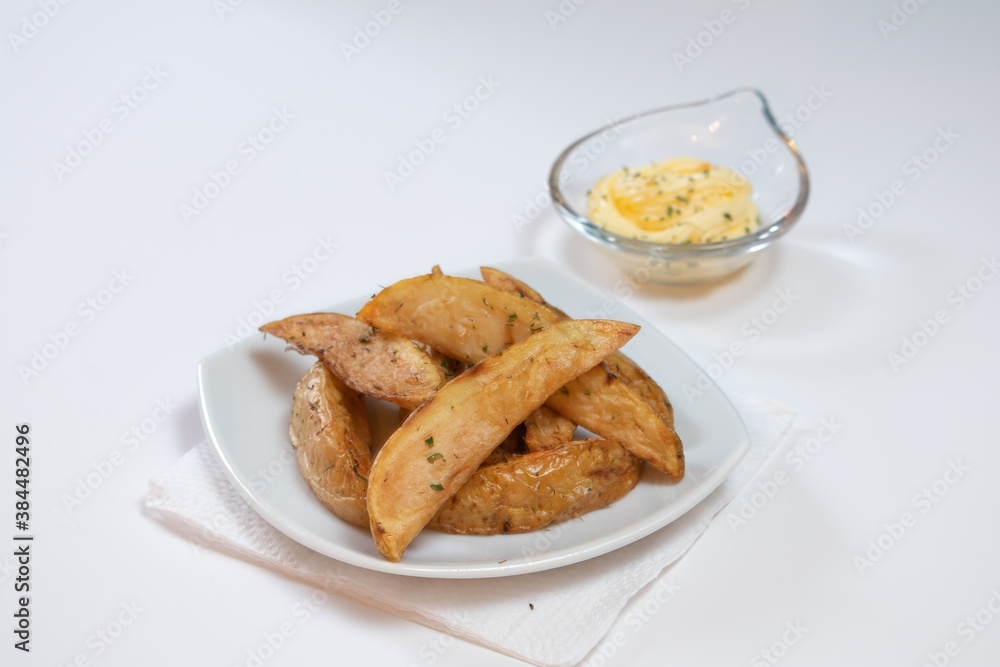 Rustic or Country Style Herb Fries potatoes on a Small white Plate with Herb Mayonnaise on a White Surface Rustic or Country Style Herb Fries potatoes on a Small white Plate with Herb Mayonnaise on a White Surface