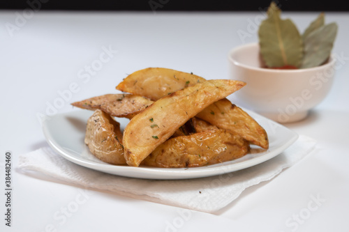 Rustic or Country Style Herb Fries potatoes on a Small Plate with BBQ Sauce on a White Surface or background