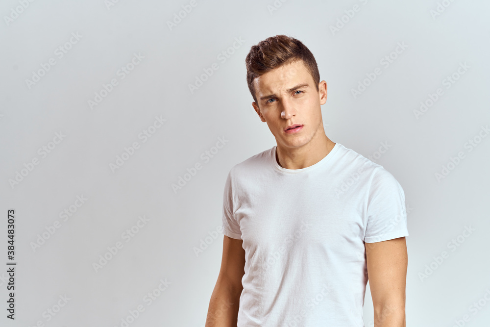 Handsome man in a white T-shirt on a light background close-up portrait cropped view Handsome man in a white T-shirt on a light background close-up portrait cropped view