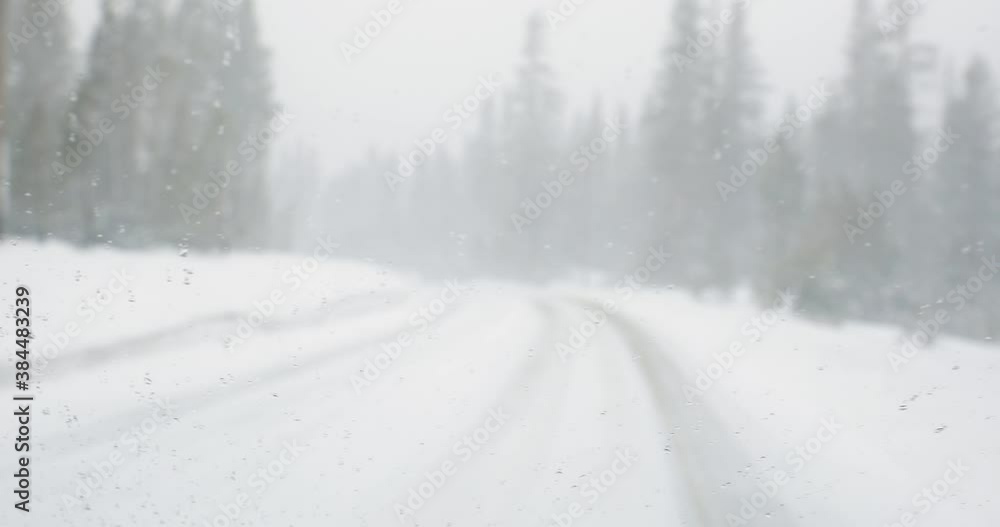 Driving on road with falling snow. Scenic view of snowy icy mountain road with pine trees. Danger travel conditions in winter, 4kDCI Driving on road with falling snow. Scenic view of snowy icy mountain road with pine trees. Danger travel conditions in winter, 4kDCI