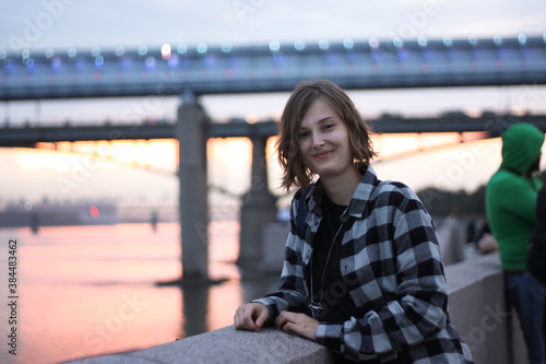 Portrait of a young smiling woman in front of a bridge