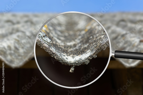 Old and very dangerous asbestos roof. Asbestos dust in the environment. Health problems. View through magnifying glass photo