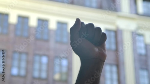 Black lives Matter. Black hand clenched in a fist in protest against the backdrop of a city street. Revolution concept. A symbol of victory, strength, power and solidarity. Close up. Slow motion. photo