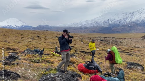 Photographer takes a photo of the nature of Kamchatka. A group of tourists at a halt. Trekking in the Klyuchevskoy volcano park. Travel to the Kamchatka Peninsula in autumn. photo