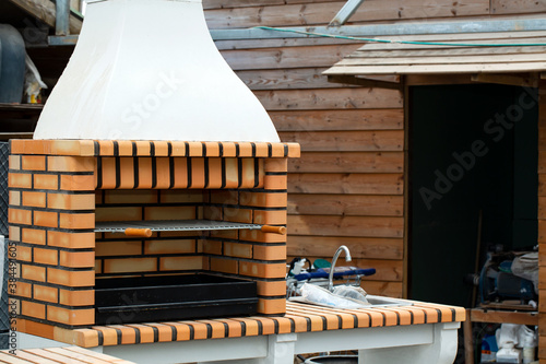 
Barbecue open fireplace for cookout food. Outdoor BBQ Grill. Open Summer Kitchen. Barbeque Grill Made From Bricks On The Backyard