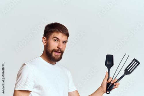 A man with kitchen appliances in the hands of their white T-shirt on a light background cropped view