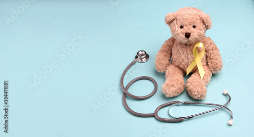 Teddy Bear yellow gold ribbon with stethoscope on blue background , Bone cancer, childhood cancer awareness, World Suicide Prevention Day, Sarcoma Awareness