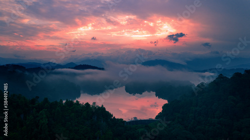 Aerial view of sunrise color reflected on the surface of a lake. Low hanging clouds added a dramatic effect to the scene.