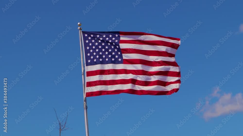 The American Flag with a blue sky backgound Slow motion The American Flag with a blue sky backgound Slow motion