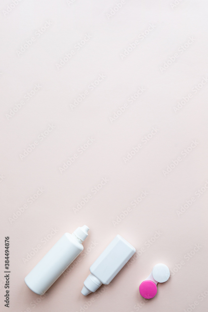 Contact lenses, lens solution and lens containers on a light pink background. Health care concept top view copy space Contact lenses, lens solution and lens containers on a light pink background. Health care concept top view copy space