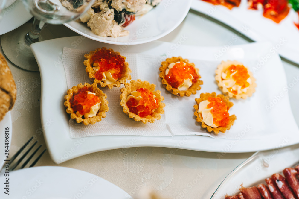 Close up of appetizing tartlets with caviar on a white plate.