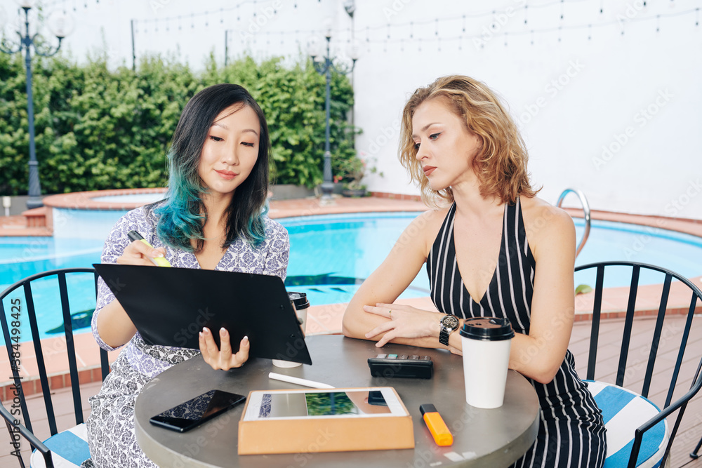 Young beautiful businesswomen discussing plans and documents at meeting Young beautiful businesswomen discussing plans and documents at meeting