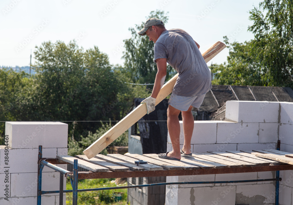 A worker builds the walls of a house from aerated concrete bricks. A worker builds the walls of a house from aerated concrete bricks.