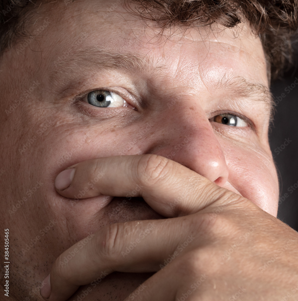 Fototapeta premium Close-up Man closes his mouth with his hand.