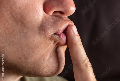 Closeup man kisses lips with finger