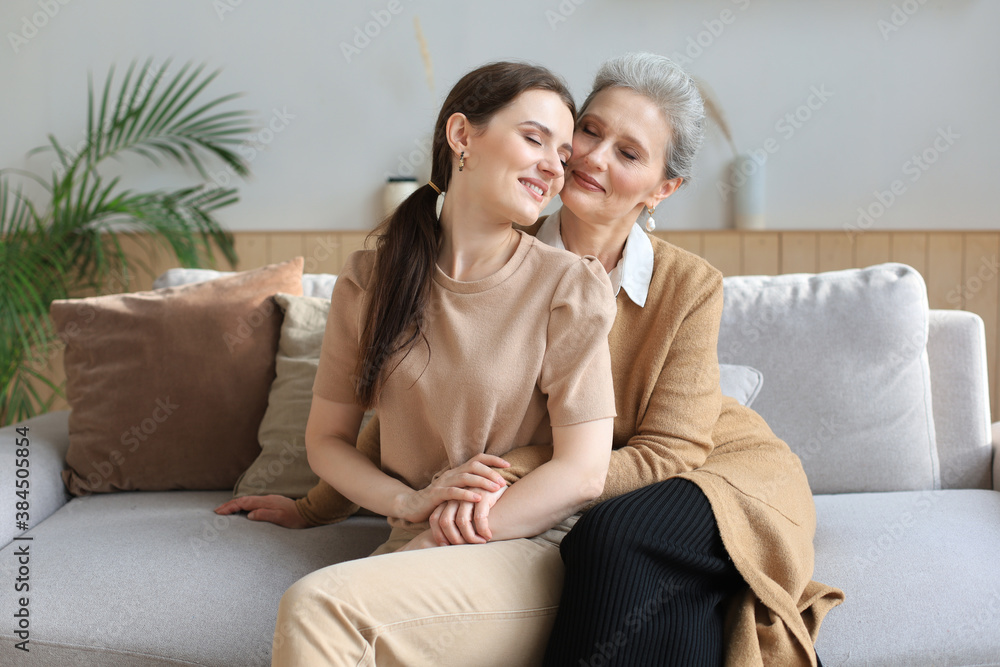 Portrait of old mother and mature daughter hugging at home. Happy senior mom and adult daughter embracing with love on sofa. Portrait of old mother and mature daughter hugging at home. Happy senior mom and adult daughter embracing with love on sofa.