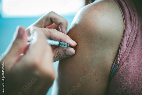 The doctor is injecting the flu vaccine on the patient s shoulder   health care concept