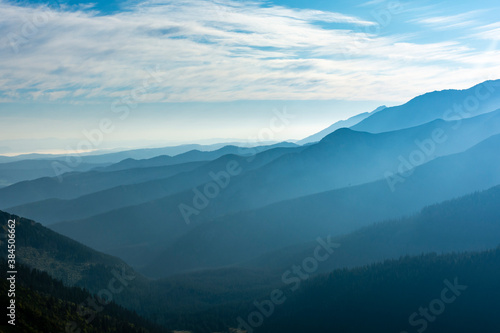 Beautiful late summer mists in the valleys between the ridges illuminated by the rays of the morning sun.