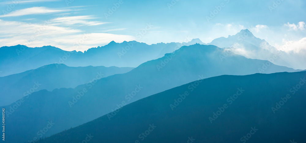 Kasprowy Wierch (Kasprov vrch) - the characteristic peak of the building at the top and the nearby ridges in the morning fog lit by the rays of the sun. Tatra Mountains, Poland.