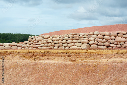 Stone boulders are stacked on the ground and used as retaining walls. It acts to resist soil erosion caused by rain.