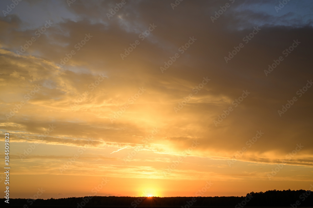 Landscape photo of the evening sunset sky in autumn against the background of a green field in the orange sun