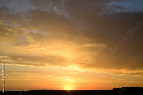 Landscape photo of the evening sunset sky in autumn against the background of a green field in the orange sun