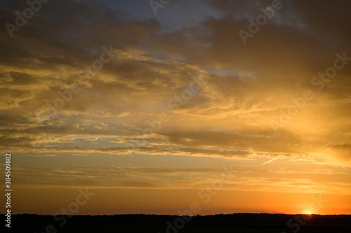 Landscape photo of the evening sunset sky in autumn against the background of a green field in the orange sun